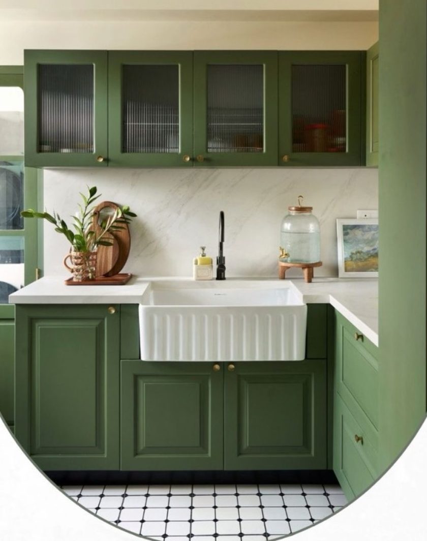 A kitchen with green cabinets, a fluted farmhouse sink and a marble splashback